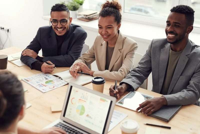 Photo of three people smiling while having a meeting 3184338
